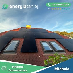 Energia Taniej Sp. z o.o. - Czerwony dach skośny z zamontowanymi panelami słonecznymi między oknami dachowymi, widok z dołu na błękitne niebo.