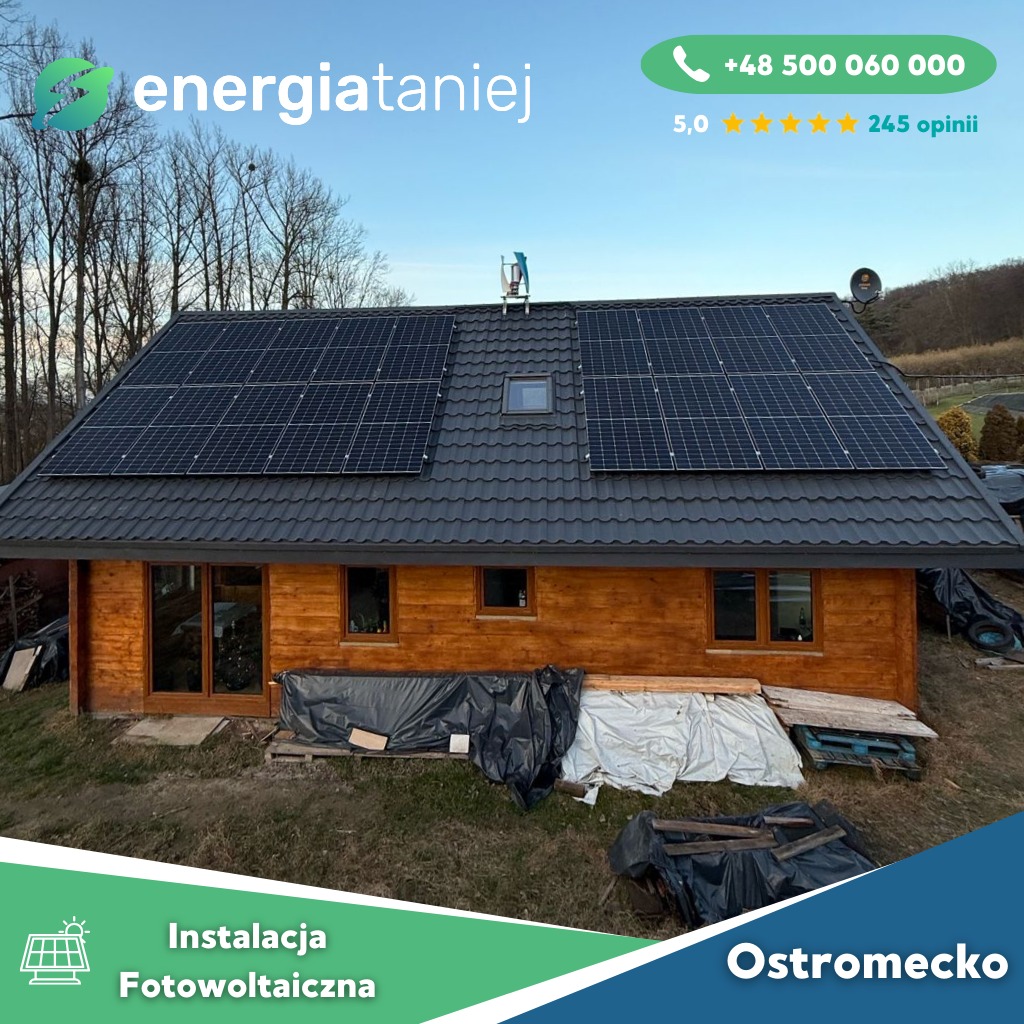 Dom jednorodzinny z panelami słonecznymi na dachu pokrytym blachodachówką w kolorze grafitowym, widoczne logo firmy 'energiataniej' oraz dane kontaktowe, na trawniku leżą zabezpieczone materiały...