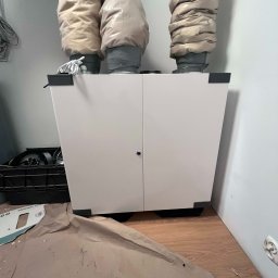 EKO NORD DANIEL ŁAGA - Biała jednostka centralna systemu wentylacji mechanicznej z trzema izolowanymi przewodami w Redzie, widoczna na podłodze kartonowa ochrona podczas montażu.