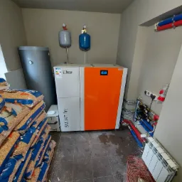 Kotłownia w Wałczu z kotłem na pellet Lazar Smart Fire, zasobnikiem wody, stertą worków z pelletem Sylva i instalacją hydrauliczną.