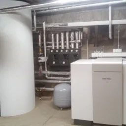 Kompletna instalacja pompy ciepła w piwnicy z dwoma zbiornikami akumulacyjnymi, rozdzielaczem hydraulicznym i jednostką sterującą Stiebel Eltron.