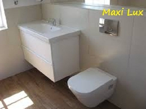 Nowoczesna, jasna łazienka z podwieszaną szafką umywalkową i toaletą. Na ścianie chromowany przycisk spłukujący. Podłoga wyłożona panelami imitującymi drewno.