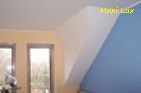 Pomieszczenie po malowaniu w Nowym Sączu: biały sufit, niebieska ściana skośna, okno w żółtej ramie. Widoczny fragment logotypu farby.