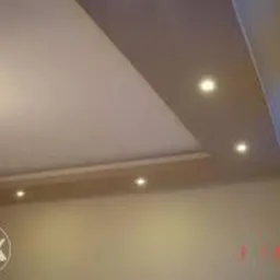 Podwieszany sufit z oświetleniem punktowym, dekoracyjna wnęka, ciepłe światło, beżowe ściany, widok pod kątem, nowoczesne wykończenie wnętrza.