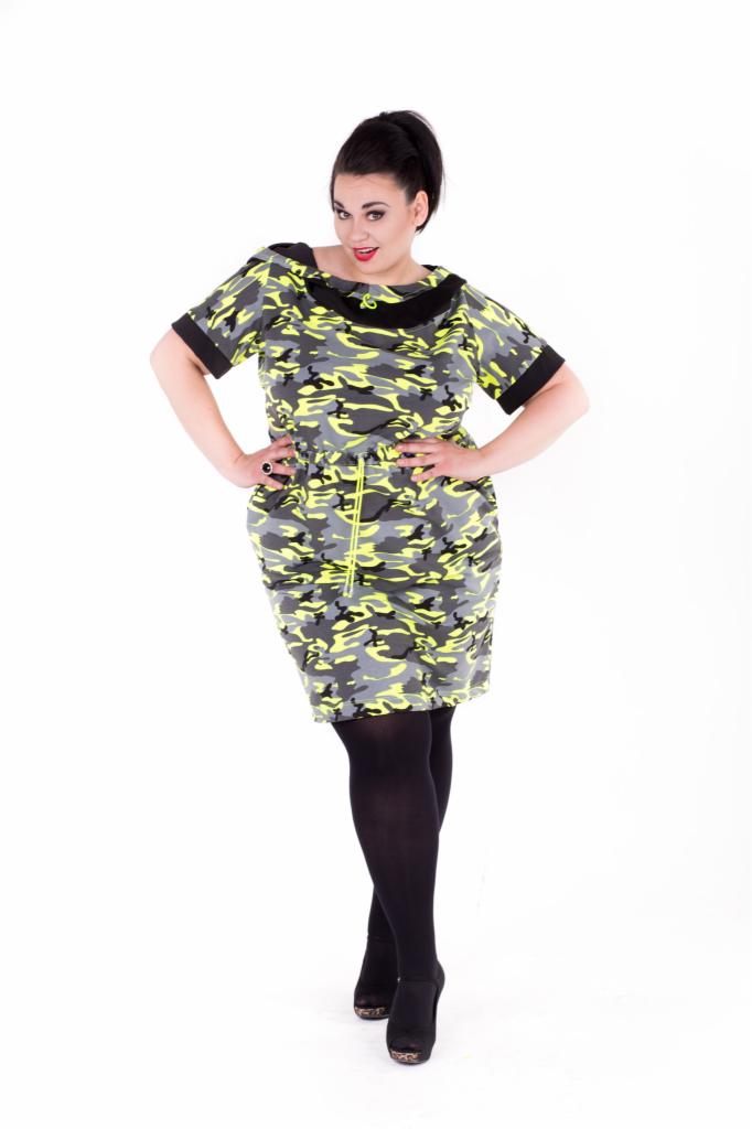 Kobieta w sukience o wzorze kamuflażu w odcieniach szarości i neonowej zieleni, z czarnymi wykończeniami, pozująca na białym tle.