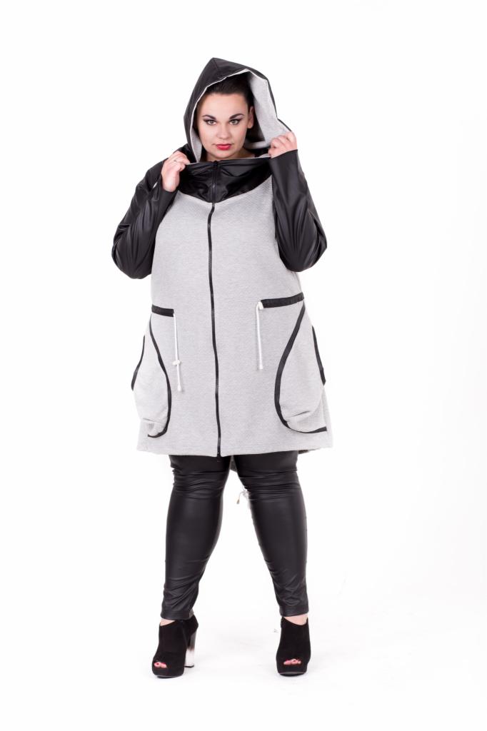 Kobieta w szarej, rozpinanej bluzie z kapturem i skórzanymi rękawami, pozująca na białym tle. Bluza z dużymi kieszeniami i czarną lamówką. Uzupełnieniem stylizacji są czarne, skórzane legginsy...