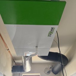 Comfort System House Tomasz Pawłowski - Centrala wentylacyjna z rekuperacją marki WANAS, widoczne podłączenia przewodów wentylacyjnych w surowym wnętrzu.