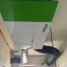 Centrala wentylacyjna z rekuperacją marki WANAS, widoczne podłączenia przewodów wentylacyjnych w surowym wnętrzu.