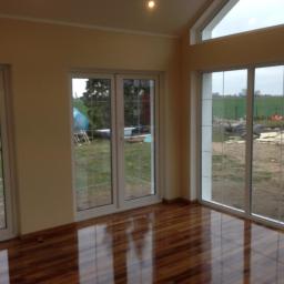 Bau - Nowoczesne wnętrze z drewnianą podłogą i dużymi oknami we Wrocławiu, widok na ogród z elementami placu budowy.