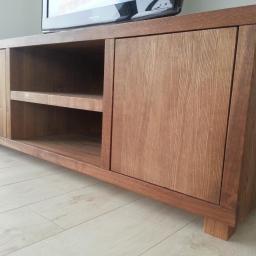 Stolarnia Solarscy - Drewniana szafka RTV z dwiema parami drzwi i otwartą półką, wykonana z dębowego drewna, stoi na jasnej podłodze. Na szafce stoi telewizor.