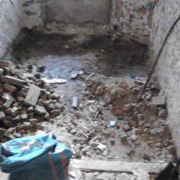 Fin end - Wnętrze pomieszczenia w trakcie demontażu: gruz, cegły i narzędzia budowlane. Widoczne ślady po skuciu tynku na ścianach z cegły.