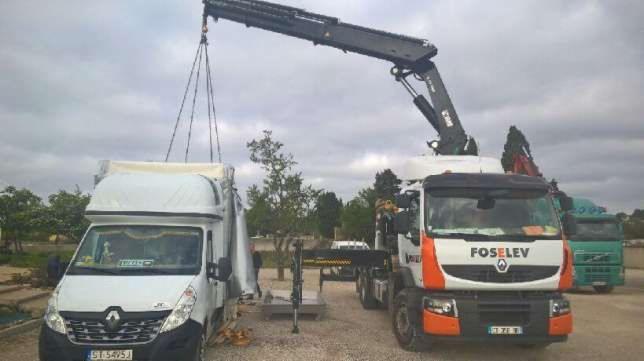 Załadunek towaru na samochód dostawczy za pomocą dźwigu, widoczny biały samochód dostawczy Renault Master i ciężarówka z dźwigiem marki Foselev.