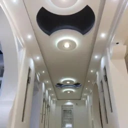 Korytarz z dekoracyjnym sufitem podwieszanym z oświetleniem punktowym i elementami z płyty karton gips w kolorze grafitowym.