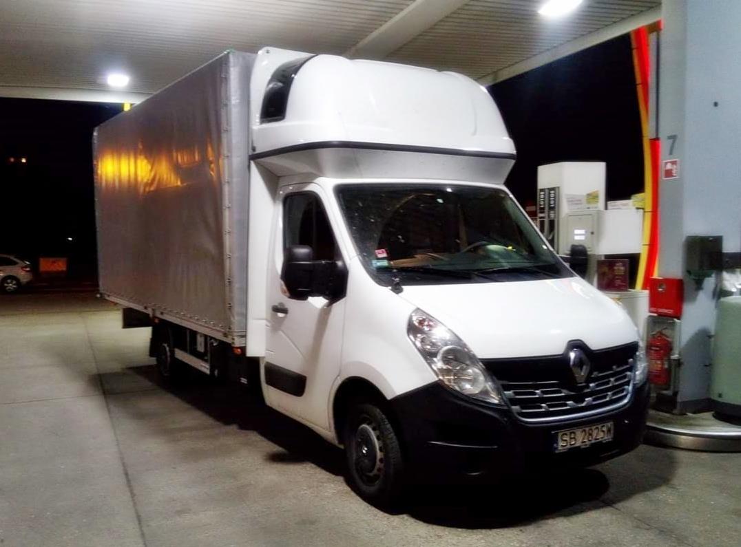Biały samochód dostawczy Renault Master z plandeką, zaparkowany na stacji benzynowej nocą, widoczne numery rejestracyjne SB 2825W.