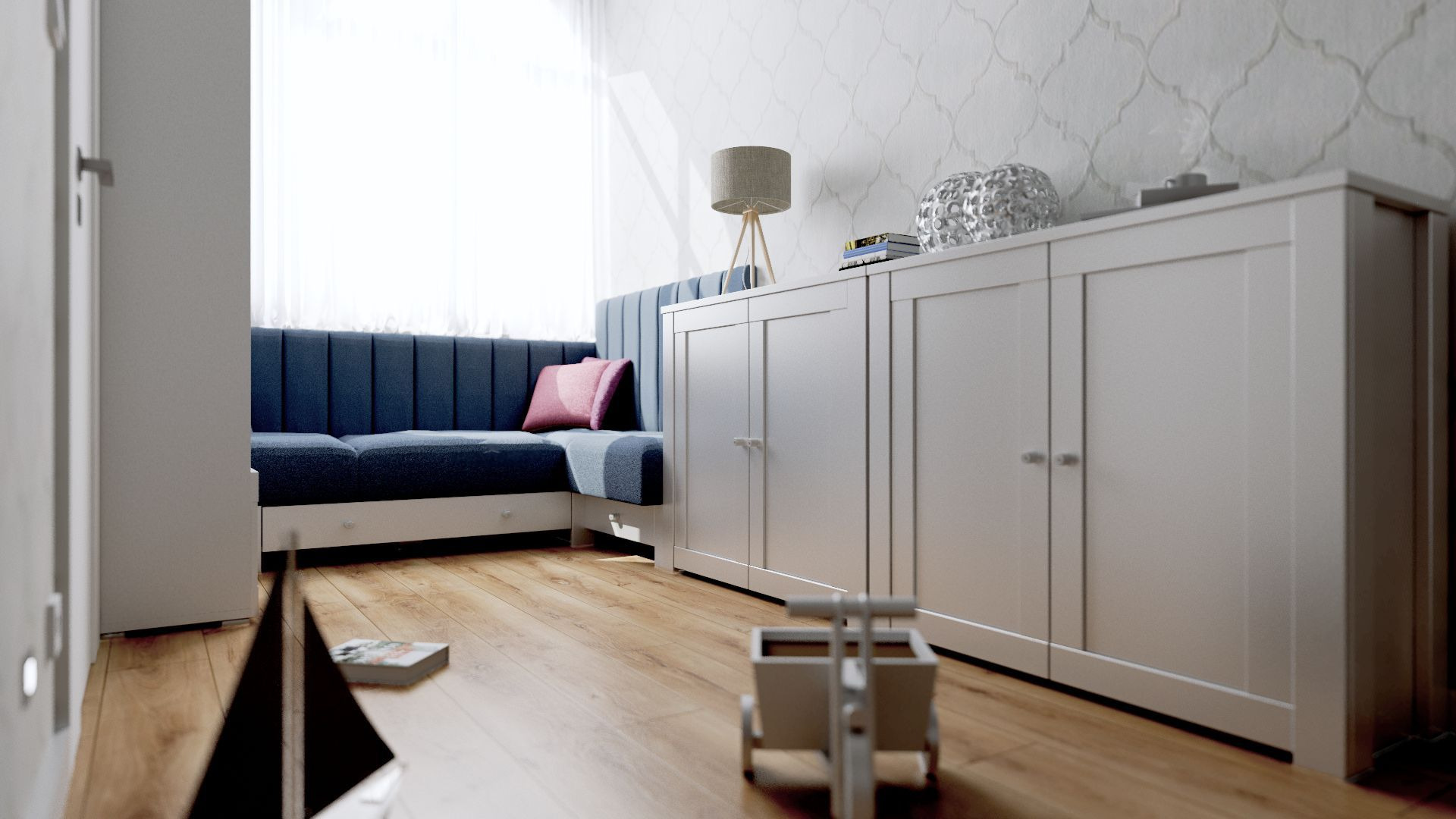Pokój dziecięcy z niebieską sofą z poduszkami, białą komodą z dekoracjami, drewnianą podłogą i zabawkami. Na ścianie tapeta we wzory.