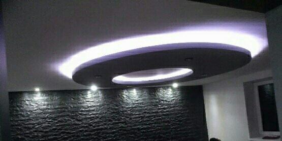 Nowoczesne wnętrze z podwieszanym okrągłym sufitem z oświetleniem LED, dekoracyjna ściana z czarnego kamienia naturalnego, oświetlenie punktowe.