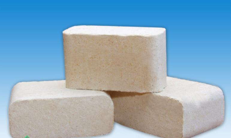 Trzy brykiety drzewne ułożone jeden na drugim na tle błękitnego gradientu, ukazujące teksturę i kształt kostek.