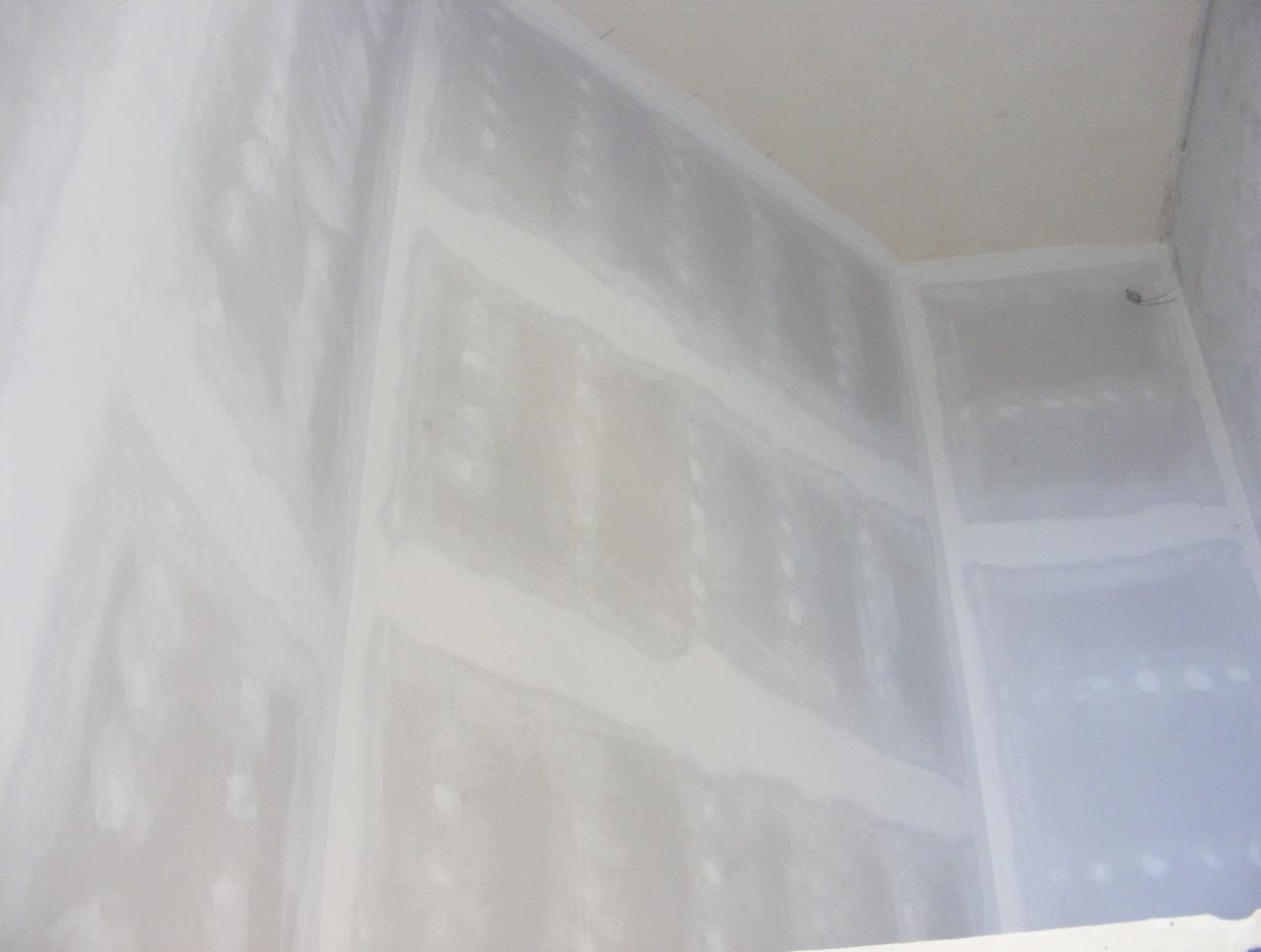 Wnętrze w trakcie prac: ściany i sufit pokryte szpachlą, widoczne łączenia płyt gipsowo-kartonowych. Przygotowanie do malowania w jasnym pomieszczeniu.