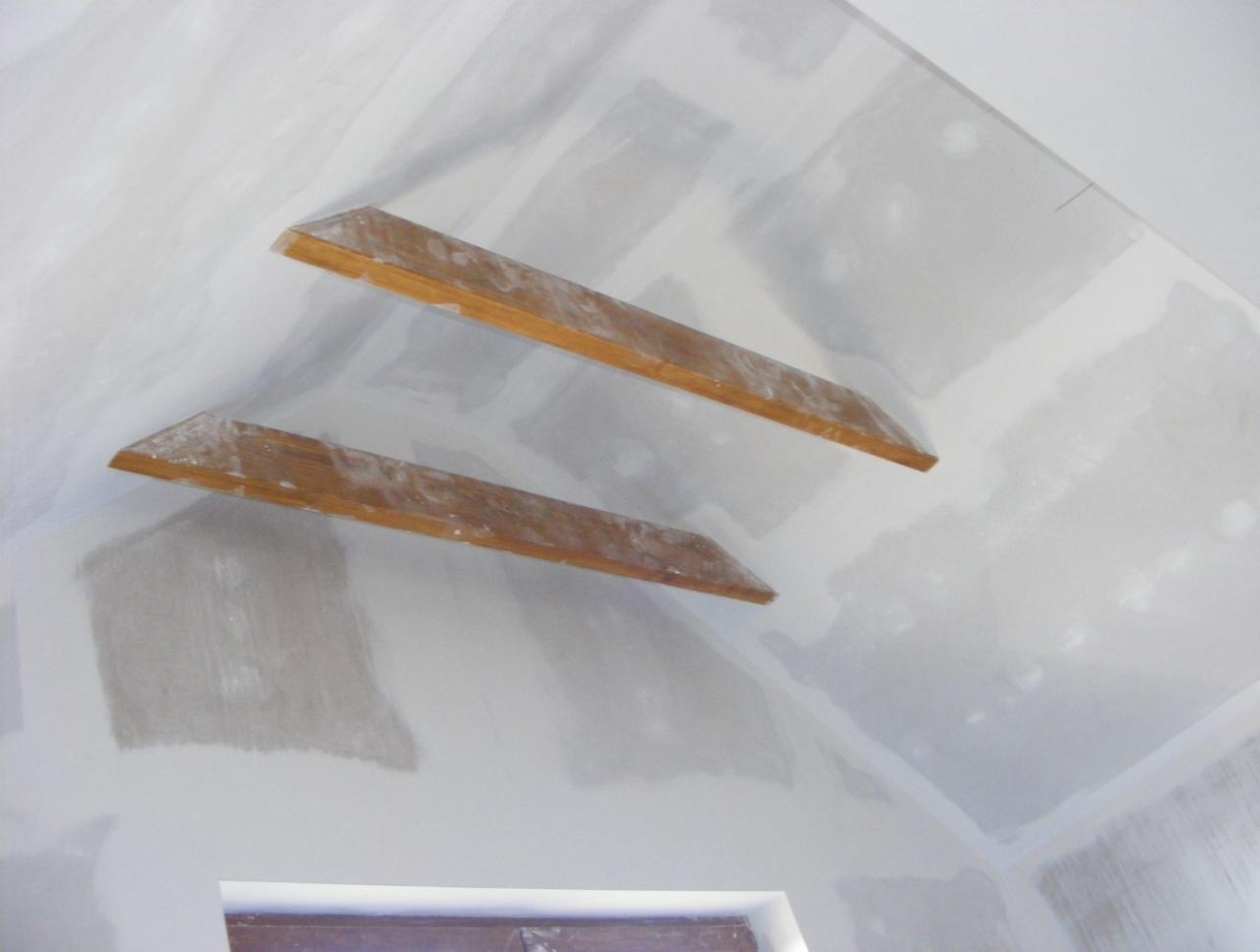 Sufit po szpachlowaniu w Piasku, widoczne drewniane listwy i świeżo nałożona gładź, gotowy do malowania. Wnętrze w trakcie wykańczania.