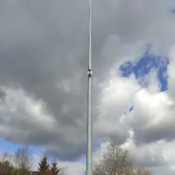 Słup oświetleniowy z dwoma reflektorami i kamerą monitoringu w Jeleniej Górze, na tle pochmurnego nieba.