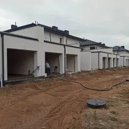 Wykończenie posadzki jastrychowej w nowo wybudowanym szeregowcu; widoczni dwaj pracownicy podczas zacierania jastrychu, jeden z nich używa zacieraczki mechanicznej