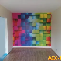 Pomalowane wnętrze z fototapetą przedstawiającą kolorowe kostki 3D na jednej ścianie, parkiet na podłodze, widoczny fragment futryny drzwiowej.
