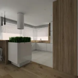 Minimalistyczna kuchnia z białymi szafkami, drewnianym blatem i akcentami drewna na ścianie, z dużą donicą z trawą i nowoczesnym okapem cylindrycznym.