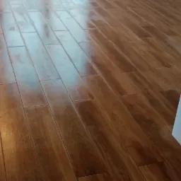 Ułożona podłoga z paneli imitujących drewno w nowym pomieszczeniu, widoczne zabezpieczenia na oknie.