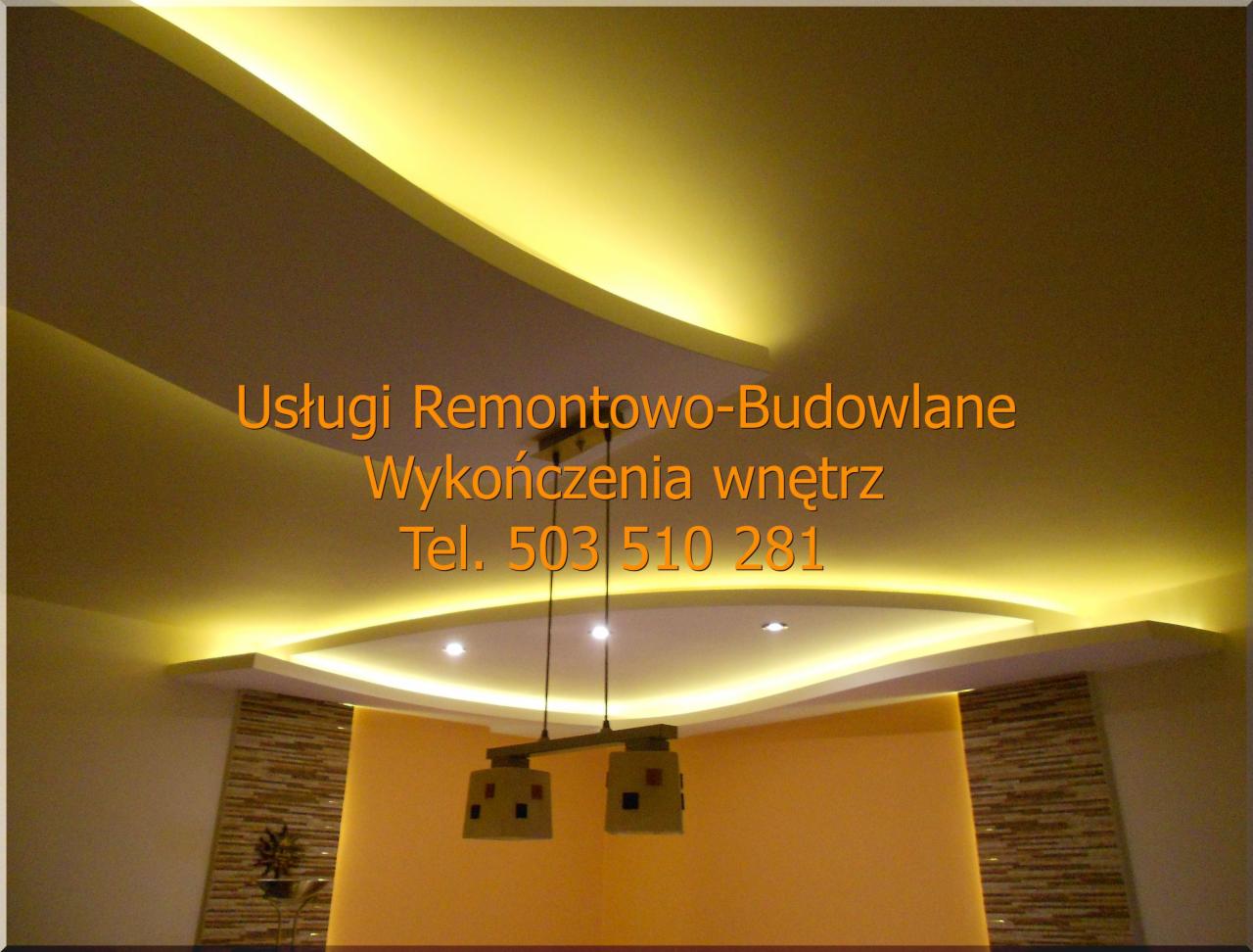 Dekoracyjny sufit podwieszany z płyt gipsowo-kartonowych z oświetleniem LED, widoczna lampa wisząca i fragment ściany z dekoracyjną okładziną.