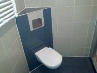 Nowoczesna toaleta podwieszana w Kartuzach. Szare płytki ścienne kontrastują z ciemną podłogą i zabudową stelaża WC, tworząc elegancki wystrój łazienki.