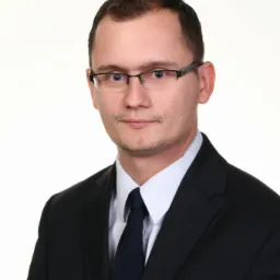 Portret mężczyzny w garniturze i okularach na jasnym tle. Profesjonalny wizerunek.