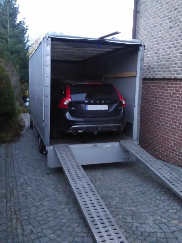 Czarny samochód Volvo na platformie lawety z najazdem, przygotowany do transportu, widok z tyłu.