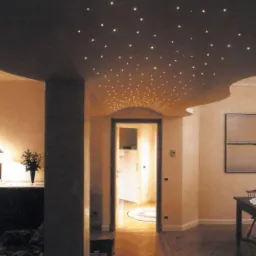 Eleganckie wnętrze z sufitem w stylu 'gwiezdne niebo', oświetlonym punktowymi lampami. Widoczne elementy dekoracyjne i meble w ciepłej tonacji kolorystycznej.
