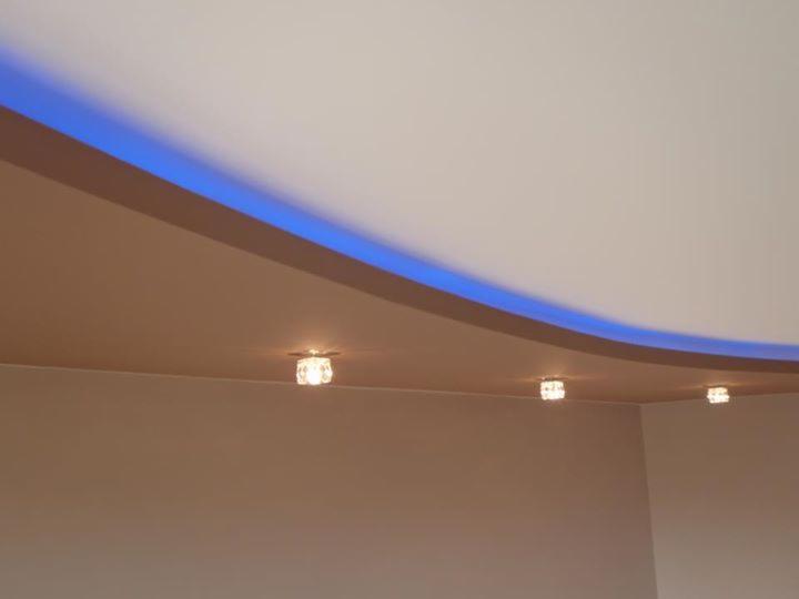 Podwieszany sufit z oświetleniem LED i trzema punktowymi lampami, kremowe ściany. Nowoczesne wykończenie wnętrza.