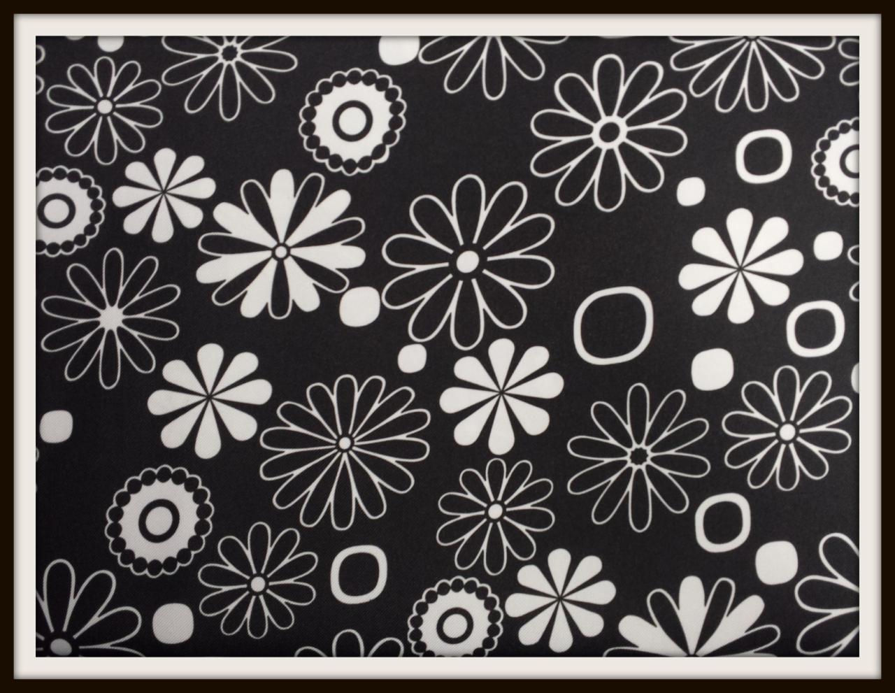 Czarno-biała tkanina w kwiaty i okręgi, wzór retro, gęsty układ motywów, kontrastowe barwy, delikatna faktura materiału.