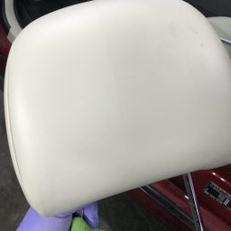 TSW malowanie mycie konstrukcje drewniane remonty - Biały zagłówek samochodowy czyszczony zieloną ściereczką przez osobę w fioletowych rękawiczkach, widoczne wnętrze samochodu.