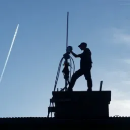 Sylwetka osoby w czapce na dachu, prawdopodobnie podczas pracy przy kominie, na tle błękitnego nieba z widocznym śladem po przelatującym samolocie.