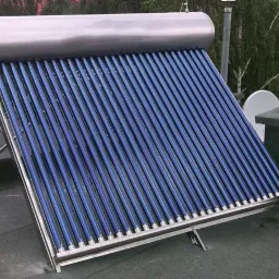 Wodny kolektor słoneczny próżniowy z rurami w kolorze intensywnego błękitu, zamontowany na płaskim dachu, z widoczną anteną satelitarną w tle.