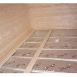 Ocieplenie podłogi: płyty izolacyjne z nadrukiem, drewniane legary, boazeria ścienna w jasnym wnętrzu. Widok z góry, ukośny kadr.