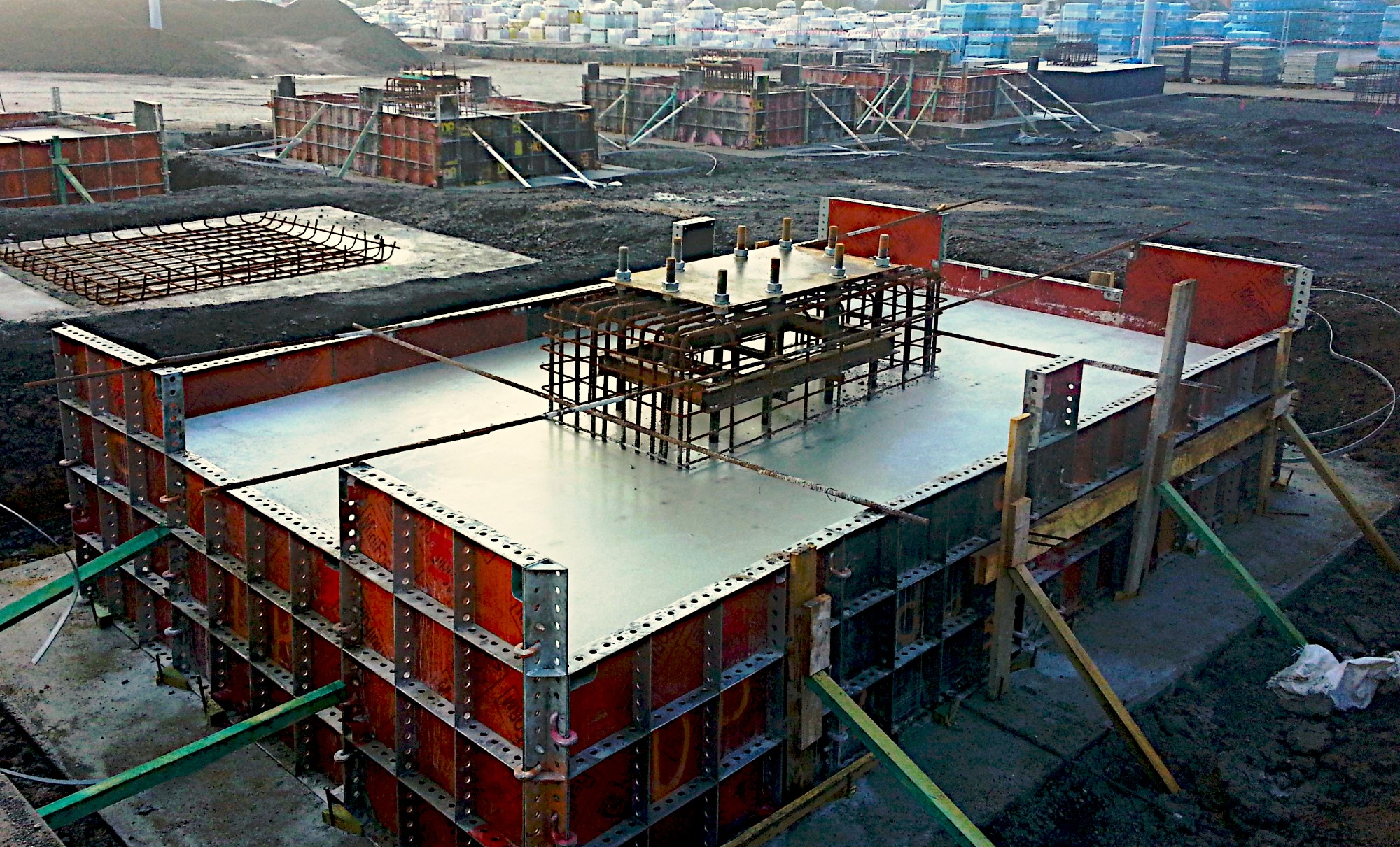 Wylany fundament z widocznym szalunkiem i zbrojeniem, przygotowany do dalszych prac na placu budowy.