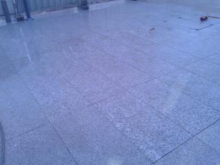 Gładka, szara nawierzchnia z płyt granitowych, świeżo po deszczu, Zwoleń. Widoczne odbicia światła na mokrej powierzchni. Minimalistyczny kadr.