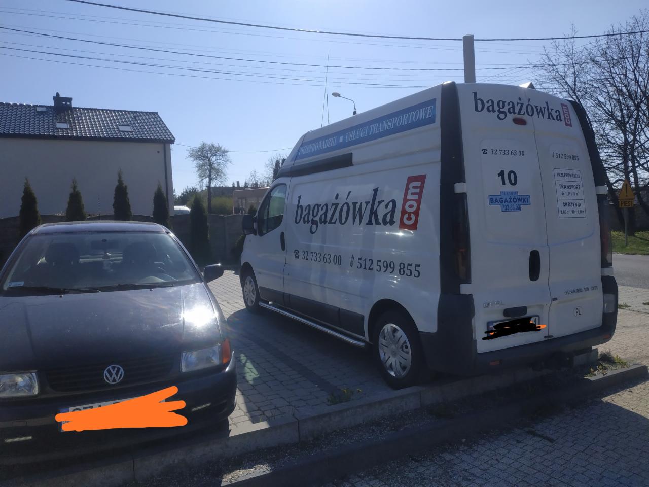 Biały bus firmy transportowej z logo 'bagażówka.com' zaparkowany na kostce brukowej obok czarnego samochodu osobowego, w tle budynek mieszkalny i drzewa.