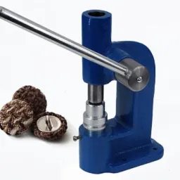 Niebieska prasa ręczna do nabijania guzików tapicerowanych obok trzech guzików, jeden przecięty, ukazujący metalowy rdzeń.