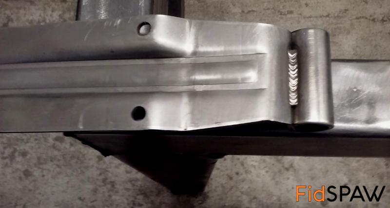 Detal spawu na metalowej konstrukcji. Precyzyjne łączenie rur i profili z widocznymi śladami obróbki. Szlifowane powierzchnie i otwory montażowe.