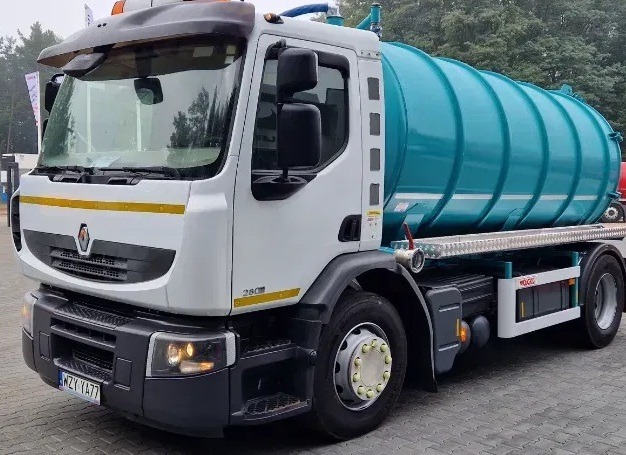 Ciężarówka Renault z turkusowym zbiornikiem asenizacyjnym, zaparkowana na szarym placu, widoczny numer rejestracyjny WZY YA77.