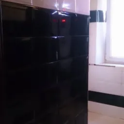 Częściowo wykończona łazienka z pionowymi pasami czarnych i białych płytek, widoczne niedociągnięcia na suficie i przy oknie.