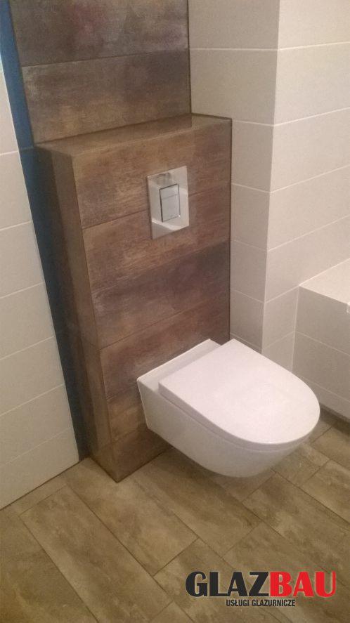 Nowoczesna łazienka: podwieszana toaleta z zabudową z płytek imitujących drewno, białe płytki na ścianach, drewnopodobna podłoga. Minimalistyczny design.