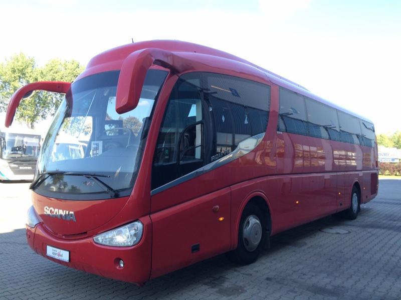 Czerwony autokar Scania Irizar na parkingu, widok z przodu, światło dzienne. Detal: charakterystyczne lusterka i logo Scania na masce.