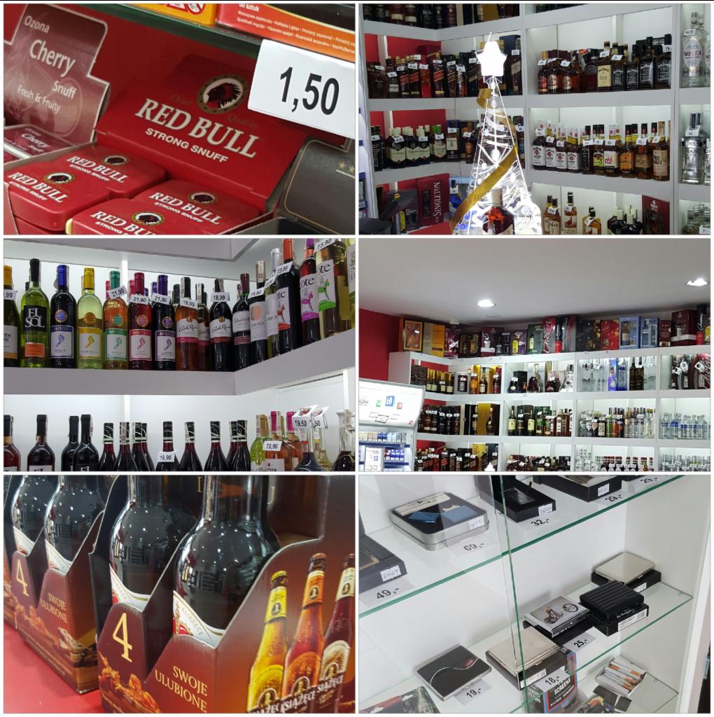 Szeroki wybór alkoholi na półkach sklepowych, w tym wina, whisky i piwa, z dekoracyjną choinką z butelek w tle.