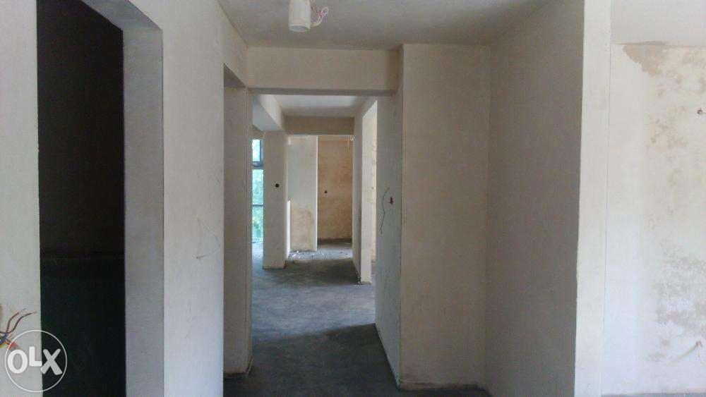 Wnętrze w trakcie tynkowania maszynowego: surowe ściany z widocznymi niedoskonałościami, przygotowane do dalszych prac wykończeniowych, z widocznymi przewodami.